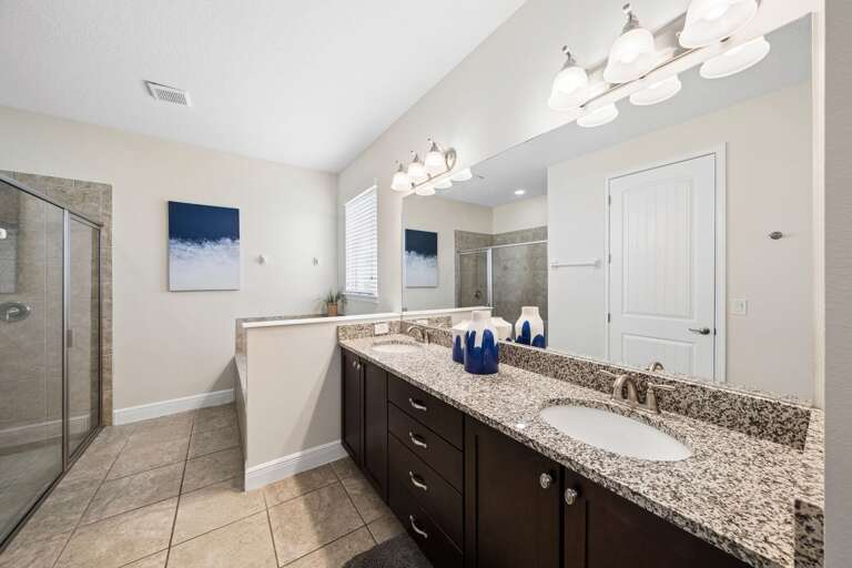 Bathroom with dual sinks and glass enclosed shower