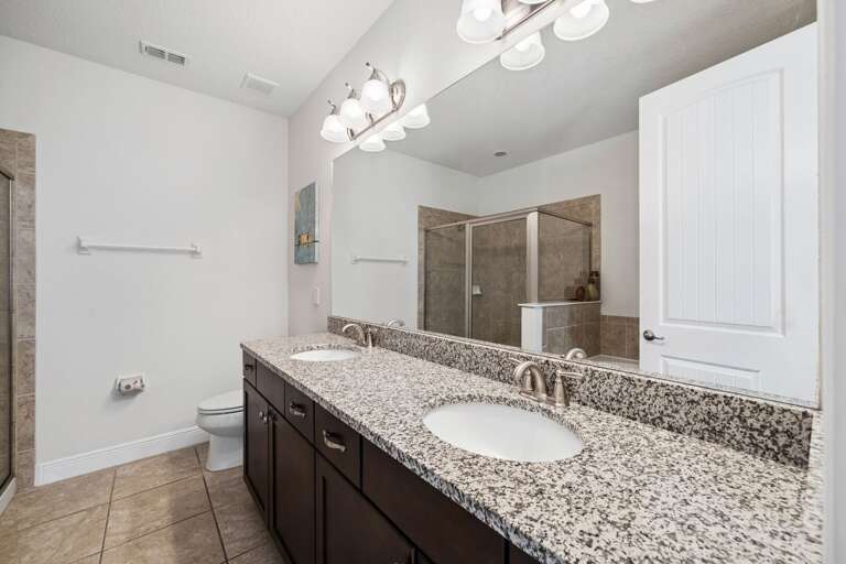 Bathroom with dual sinks and glass enclosed shower