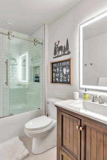 Bunk room ensuite bathroom includes a shower/tub combination with vanity, high end electric mirror, and toilet.