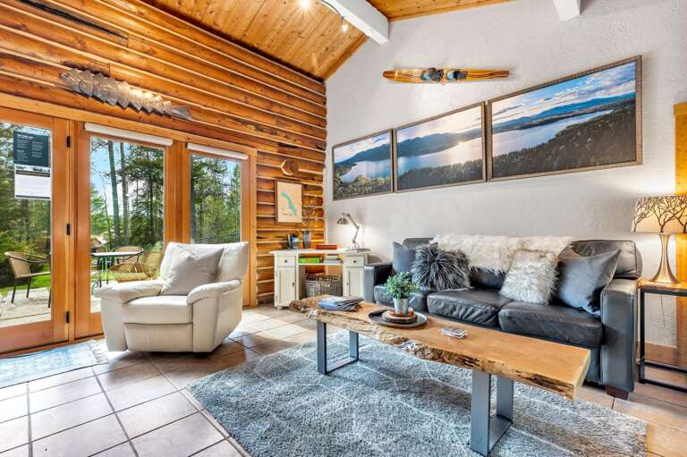 The grand living room space with vaulted ceilings, wood buring fireplace, desk, HDTV with streaming capabilities, french doors to the patio.