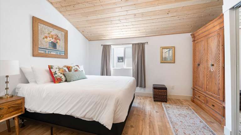 The master bedroom features vaulted ceilings, a luxurious king size mattress, armoire, and ample closet space.