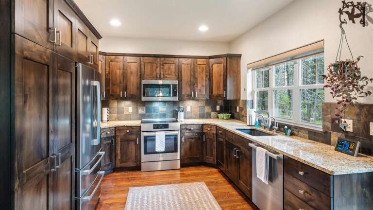 Fully stocked kitchen with top of the line appliances, induction stove top, filtered water system, and mountain and lake views from the kitchen sink.