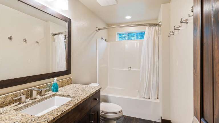 Lower level full size bathroom with shower/tub combination, toilet, and vanity.