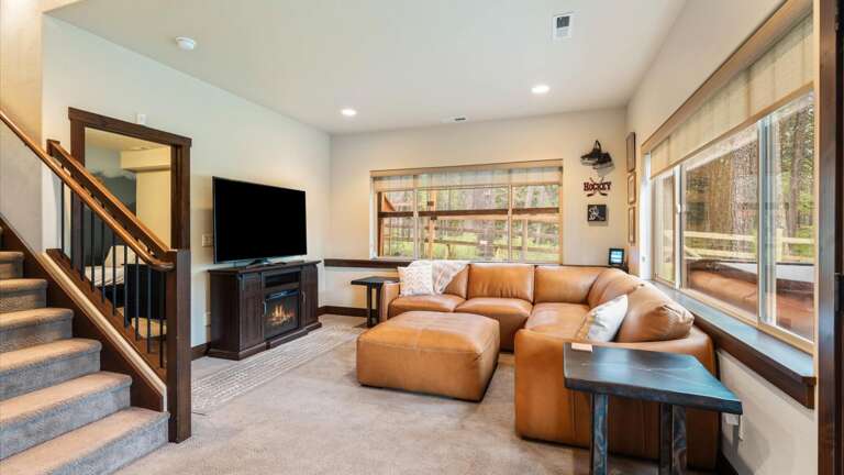 Lower level living room/tv room with luxury leather sofa, electric fireplace, HDTV with streaming capabilities and back-lit entertainment center.