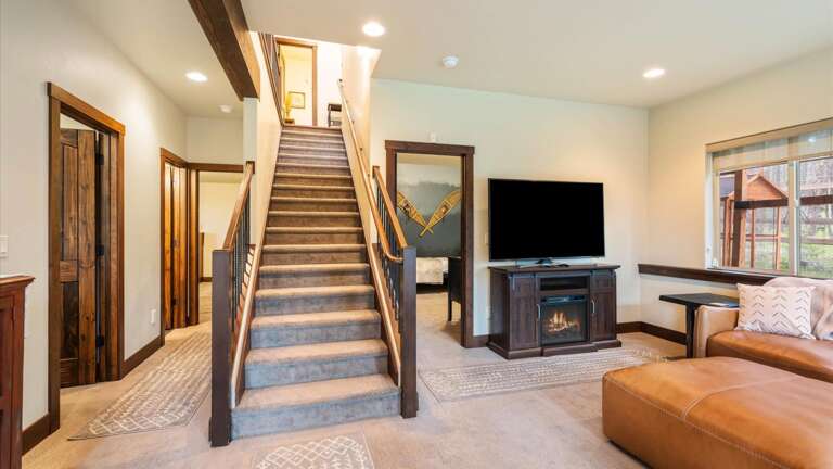 Lower level living room/tv room with luxury leather sofa, electric fireplace, HDTV with streaming capabilities and back-lit entertainment center.