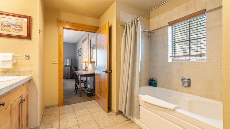 Ensuite master bathroom with double vanity, toilet, and shower tub combination.