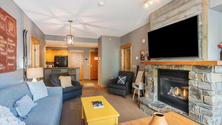 The great room features a luxury queen sofa sleeper, HDTV with streaming and cable, gas fireplace, views of the slopes, open concept kitchen, breakfast bar, dining area, and door out to the patio.
