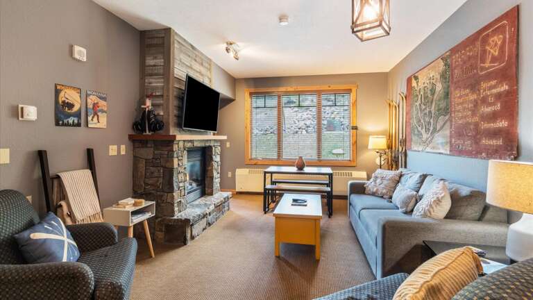 The great room features a luxury queen sofa sleeper, HDTV with streaming and cable, gas fireplace, views of the slopes, open concept kitchen, breakfast bar, dining area, and door out to the patio.