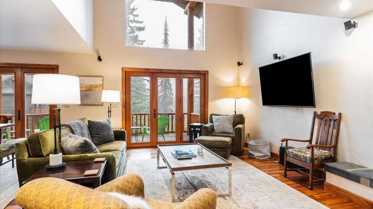 Open concept living room, kitchen, and dining area with gas fireplace, vaulted ceilings, wrap around balcony, and HDTV with streaming capabilities.