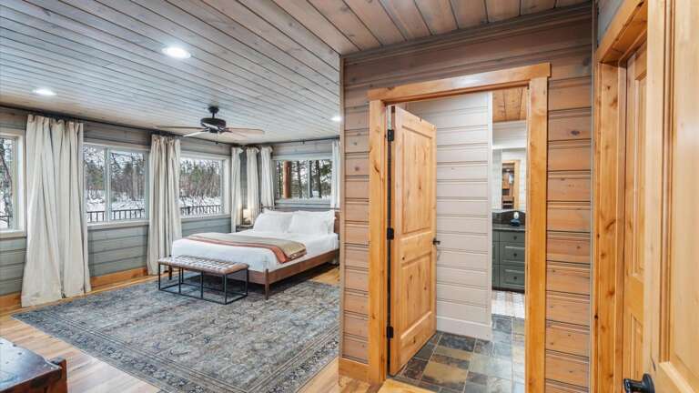 The main floor master suite features lake views from the comfort of this California King Bed, HDTV with streaming capabilities, a walk-in closet,