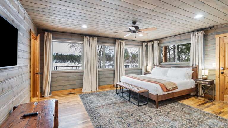 The main floor master suite features lake views from the comfort of this California King Bed, HDTV with streaming capabilities, a walk-in closet,