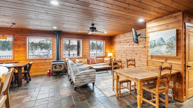The open concept main floor features the living room, dining area, wood burning stove, kitchen, and views of the lake from every angle.