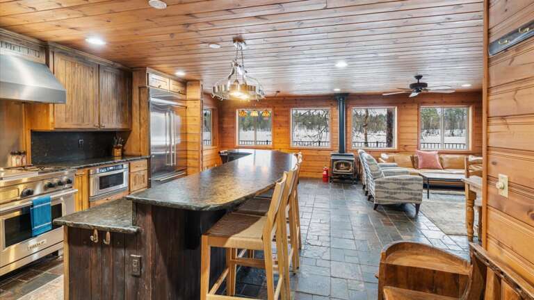 The open concept main floor features the living room, dining area, wood burning stove, kitchen, and views of the lake from every angle.