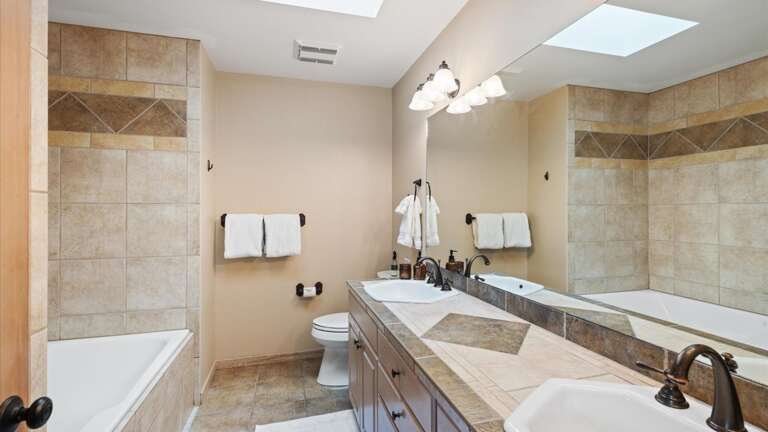 Master ensuite bathroom with double vanity, toilet, jetted tub, and walk-in shower.