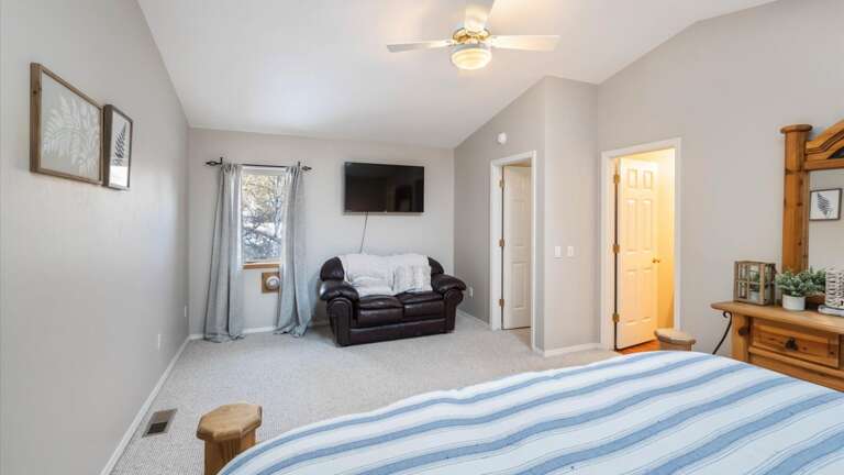 Master bedroom with vaulted ceilings, walk-in closet, HDTV with streaming capabilities, seating area, and ensuite bathroom.
