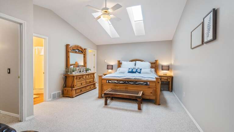 Master bedroom with vaulted ceilings, walk-in closet, HDTV with streaming capabilities, seating area, and ensuite bathroom.