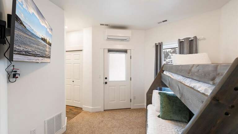 The lower-level bunk room features a full bed on the bottom and a twin bed on top. This room also features an HDTV with streaming capabilities, an ensuite bathroom, and a closet.