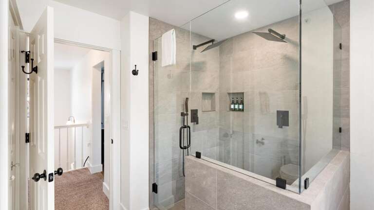 The newly renovated top-floor master bathroom features a large walk-in shower with a double rain shower, a large vanity, a toilet, and a laundry closet.