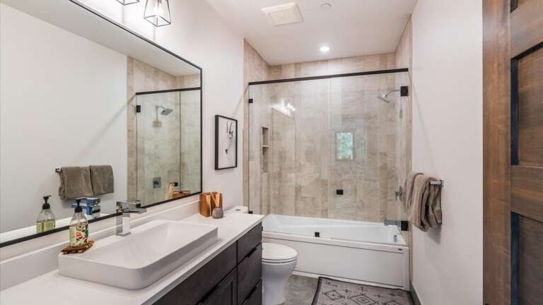 Guest bathroom includes a luxury shower/tub combination, toilet and vanity.