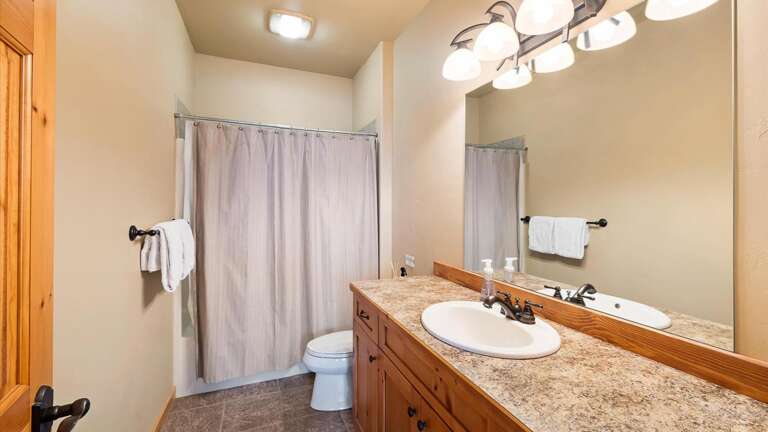Ground level bedroom ensuite bathroom with shower tub combination, large vanity,