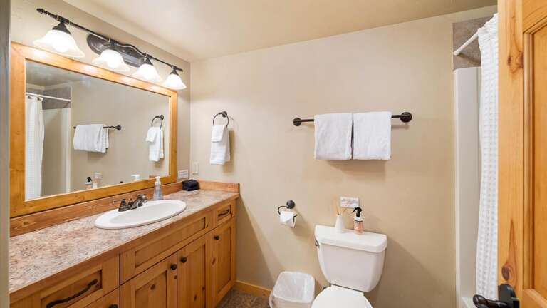 Main floor bedroom #2  ensuite bathroom with shower/tub combination, vanity, and toilet.