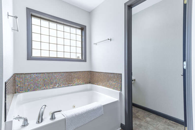 Enjoy the light colors soaker tub with tile surround and double vanity in the primary.