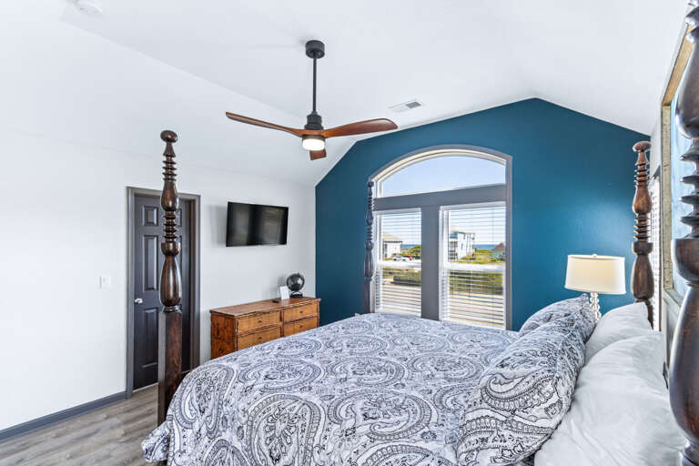 Tranquil bedroom with a 4-post King-sized bed, modern ceiling fan, and a ocean view.