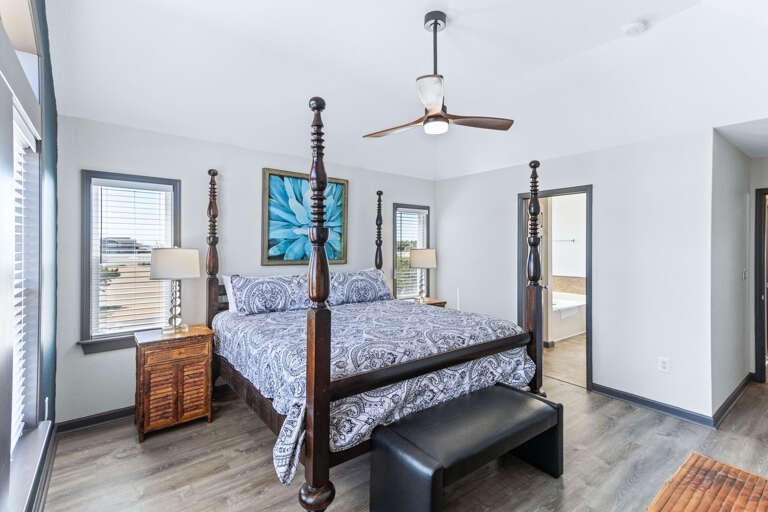 Tranquil bedroom with a 4-post King-sized bed, modern ceiling fan, and a ocean view.
