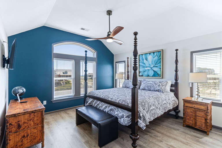 Tranquil bedroom with a 4-post King-sized bed, modern ceiling fan, and a ocean view.