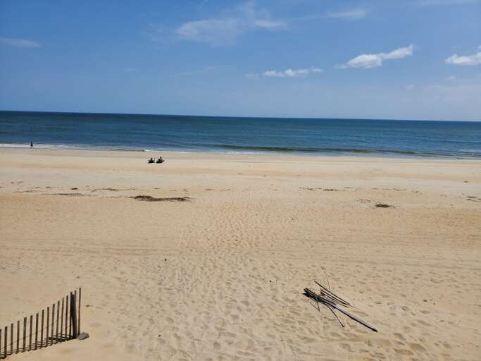 Sandy Shore Sweeps By Serene Sea, Sparse Sunbathers Sprawl Silently