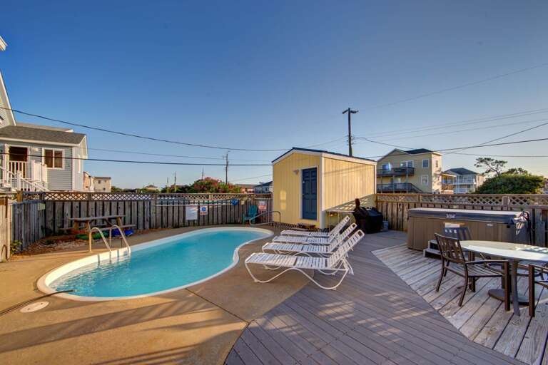 Backyard Swimming Pool With Deck Chairs And Dining Table