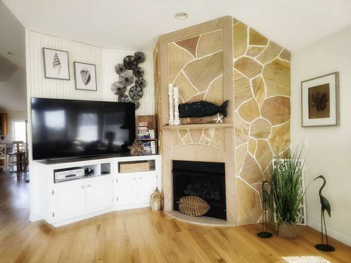 Living Space With Stone Fireplace And Mounted Television, Wooden Floors And Minimalistic Decor
