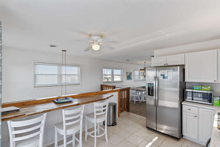 Sleek, Spacious Kitchen With Stainless Steel Appliances And Bar Stools By A Breakfast Bar