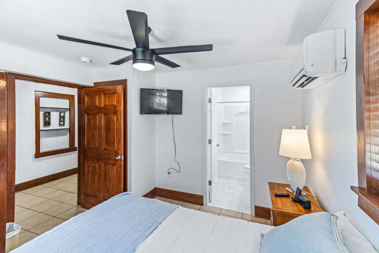 Interior Of A Bedroom With Double Bed, Ceiling Fan, TV, And Open Door