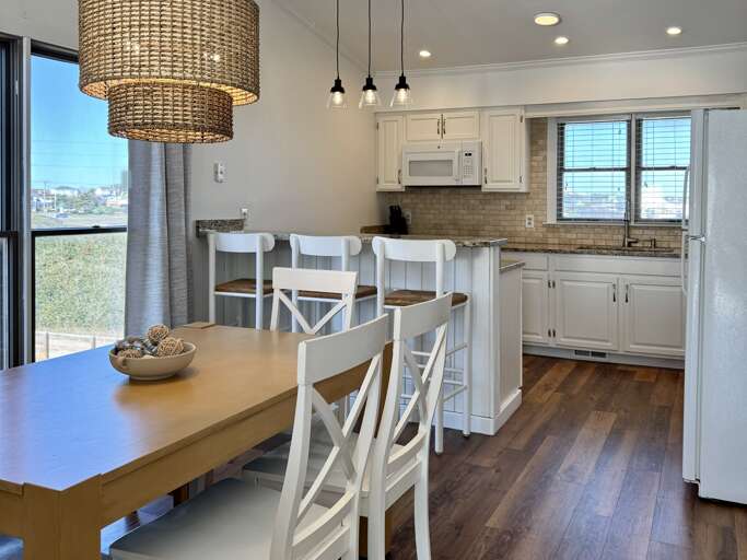 Bright Kitchen With Wooden Dining Set, Woven Light Fixture, White Cabinetry