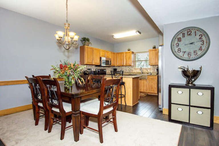Spacious Kitchen And Dining Area With Large Clock And Wooden Cabinets