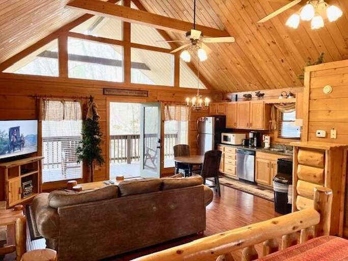 Wooden-walled Living Space With Beams, Balcony View, And Brown Furniture