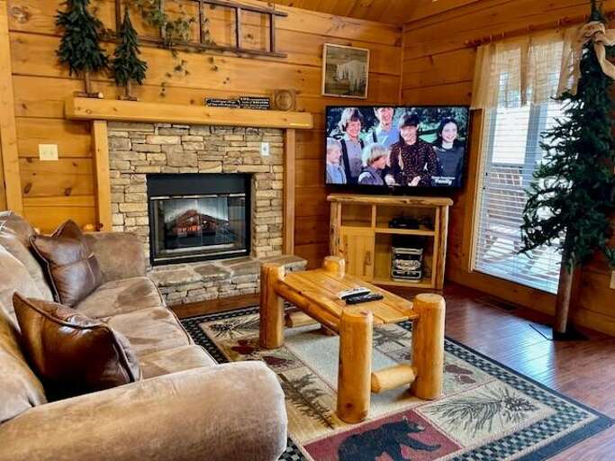 Rustic Room With Stone Fireplace, Wooden Walls, And TV