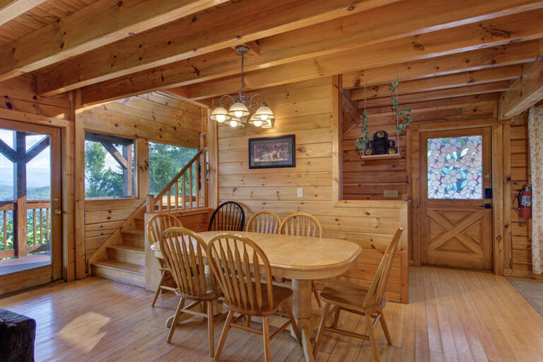 Wooden Dining Area With Round Table And Chairs, Open Door To Deck