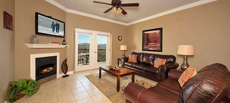 Living Room With Leather Furniture, Fireplace, And TV, Leading To Balcony