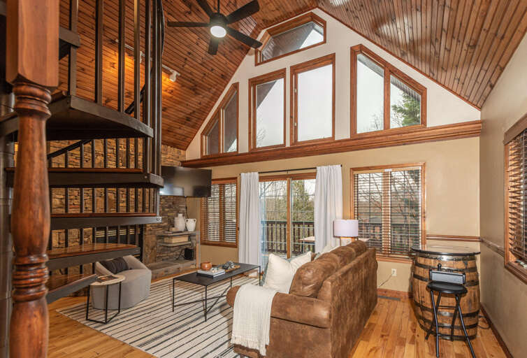 High-ceilinged Living Space In A Vacation Rental With Expansive Windows And A Wooden Staircase
