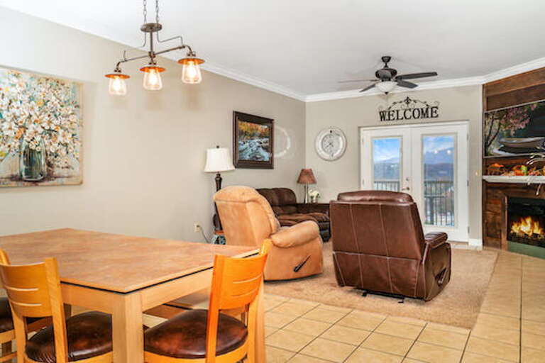 Living Space With Leather Chairs, Dining Table, Ceiling Fan, And Fireplace