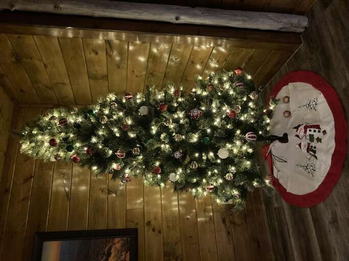 Christmas Tree Trimmed With Twinkling Lights And Red Baubles In A Timbered Room