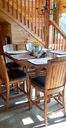 Wooden Dining Table Set Beneath Staircase In Sunlit Space