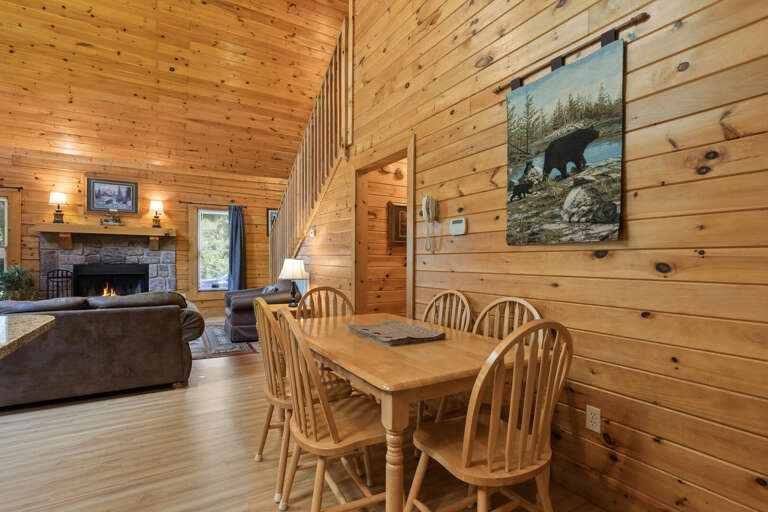 Interior With Wooden Walls, Dining Table, Fireplace, And Bear Painting
