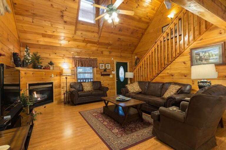 Wooden Cabin Interior With A Staircase, Sofas, And Fireplace