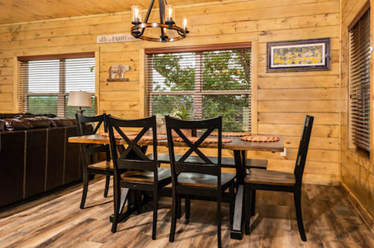 Rustic Room With Wooden Walls And Dining Table Set Under Chandelier