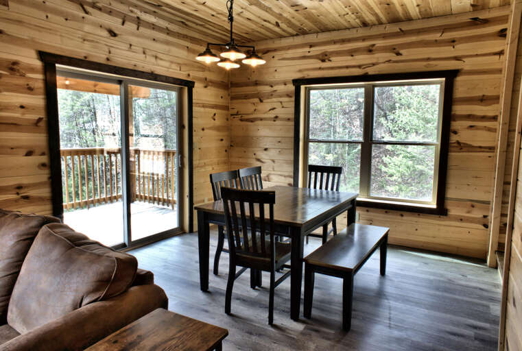 Wood-paneled Room With Windows, Wooden Table And Chairs, Deck Access