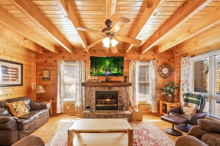 Wood-paneled Living Room With Ceiling Fan And Fireplace, Furnished With Sofas And A Coffee Table
