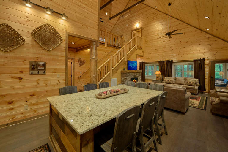 Wood-paneled Interior With Loft, Large Kitchen Island, Sofas, And Ceiling Fan